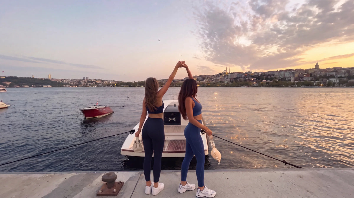 Twee vrouwen in de Midnight set en de Navy set bij het water bij zonsondergang