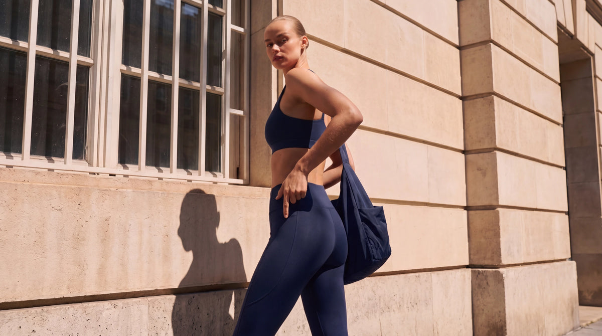 Model in de Midnight sportset met tas, kijkt over haar schouder